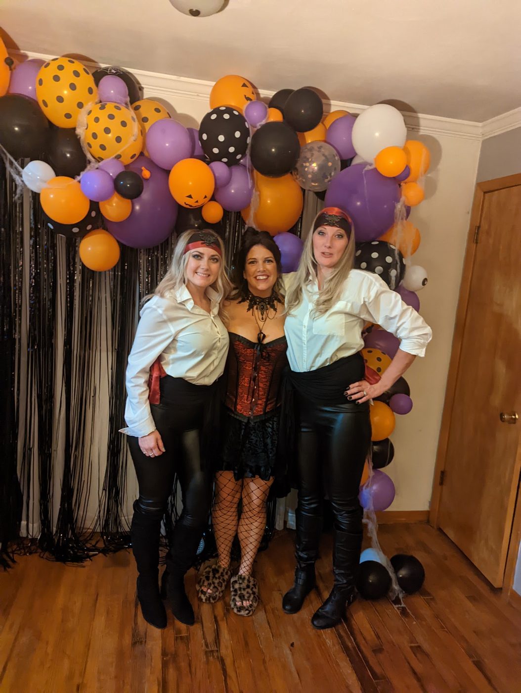 Three pirates in corsets and white shirts posing at the balloon arch