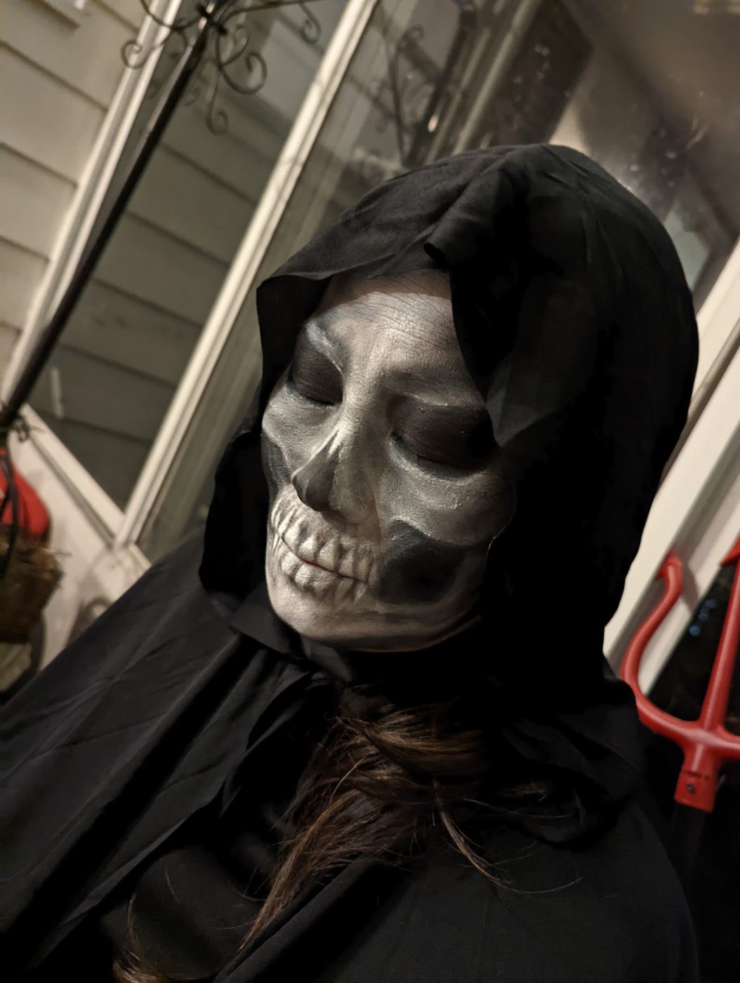 A hooded figure in a skull mask
